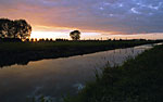 Sunset with cloudcover over small ditch.